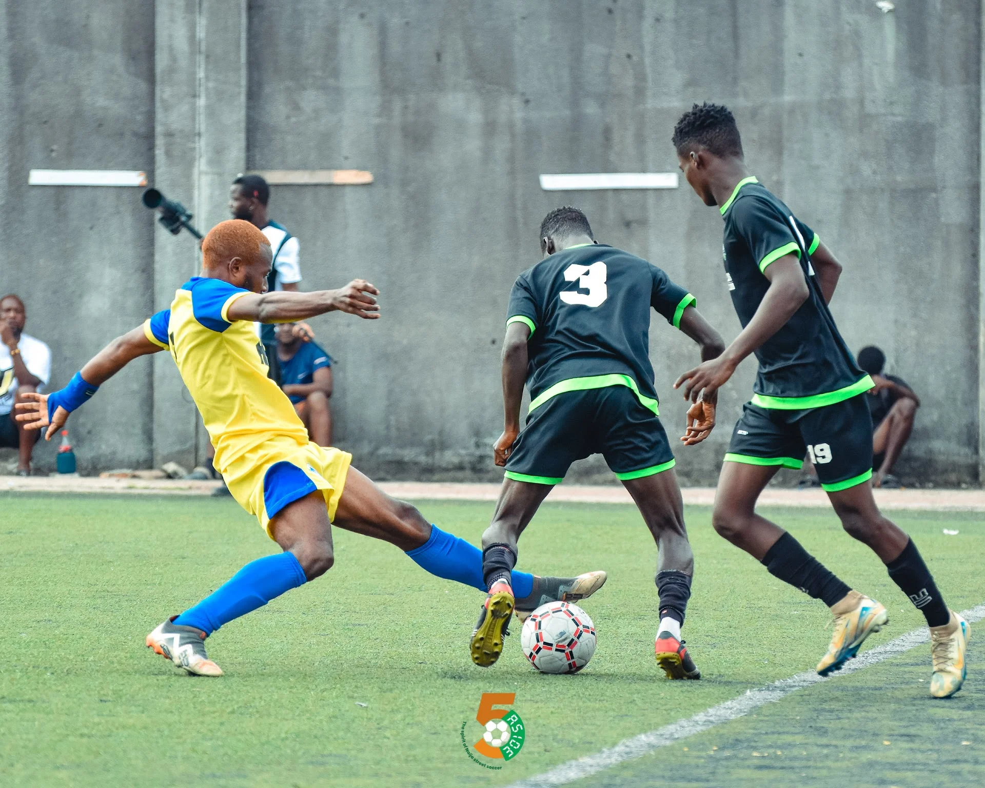 Shegx taking on two defenders for the ball